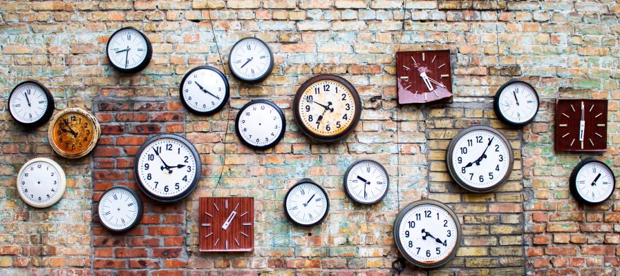 Many vintage clocks on a brick wall