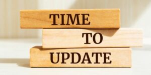 Three wooden blocks with the words "time" "to" and "update" on them. The blocks are sitting on a white surface against a light background