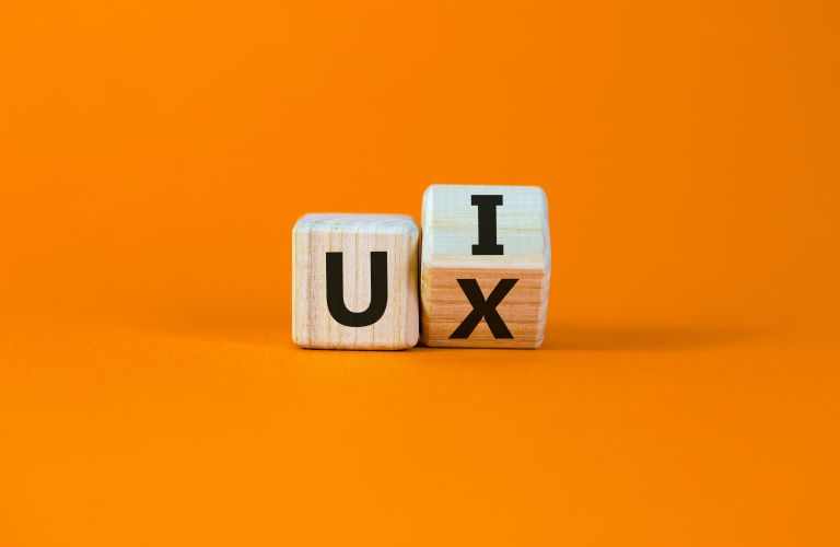 Two wooden dice, a "U" and another dice rotated showing the "I" and an "X"